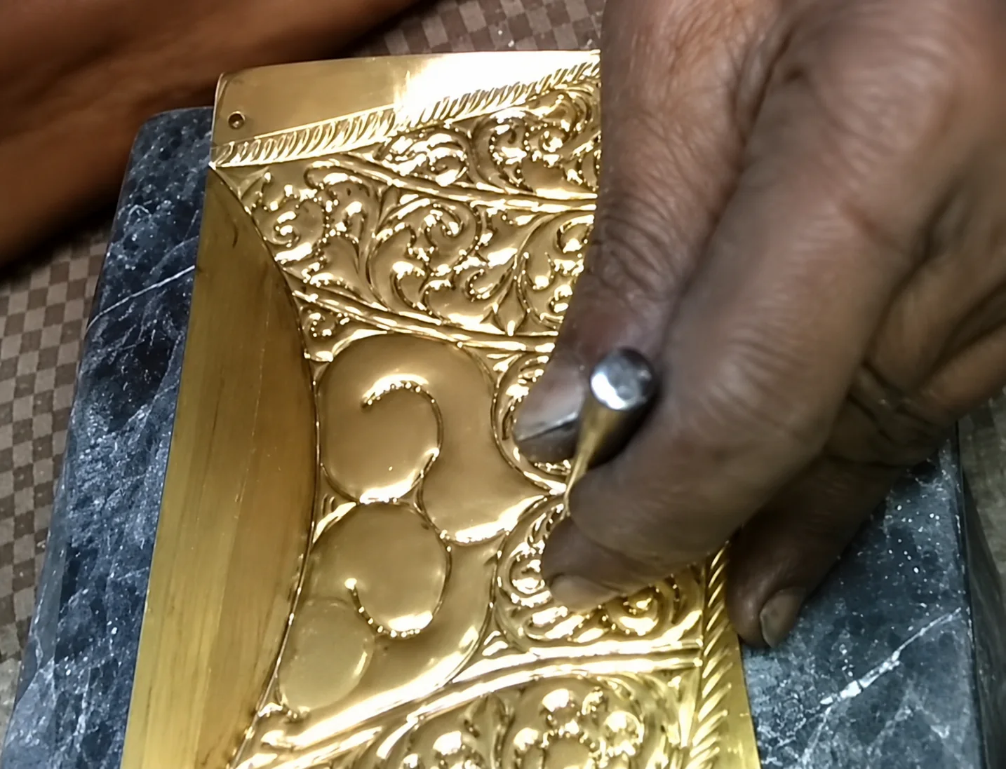 Artisan hand-chasing floral detail into metal