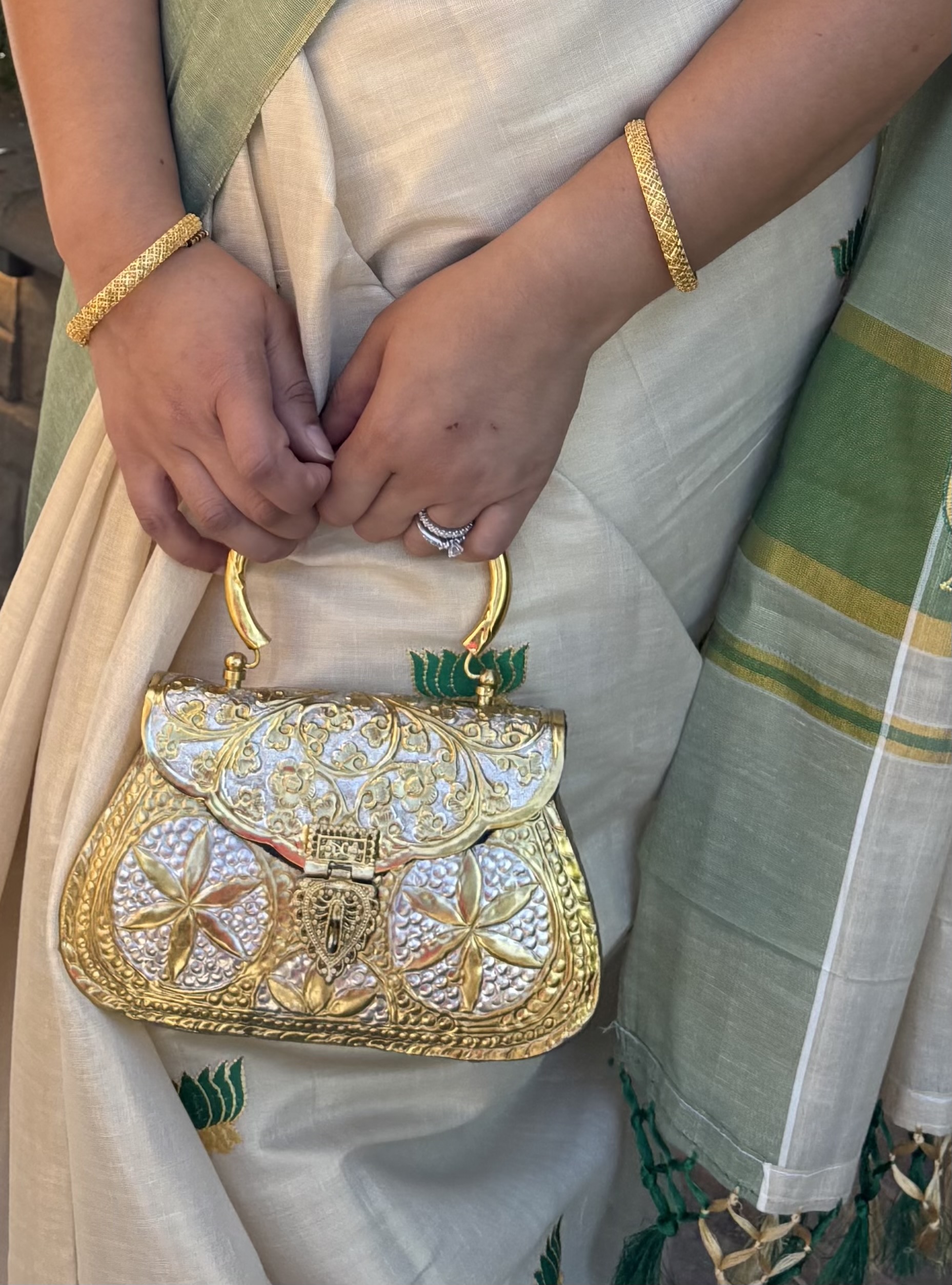 Hand carrying a gold and silver VARNA clutch with a sari
